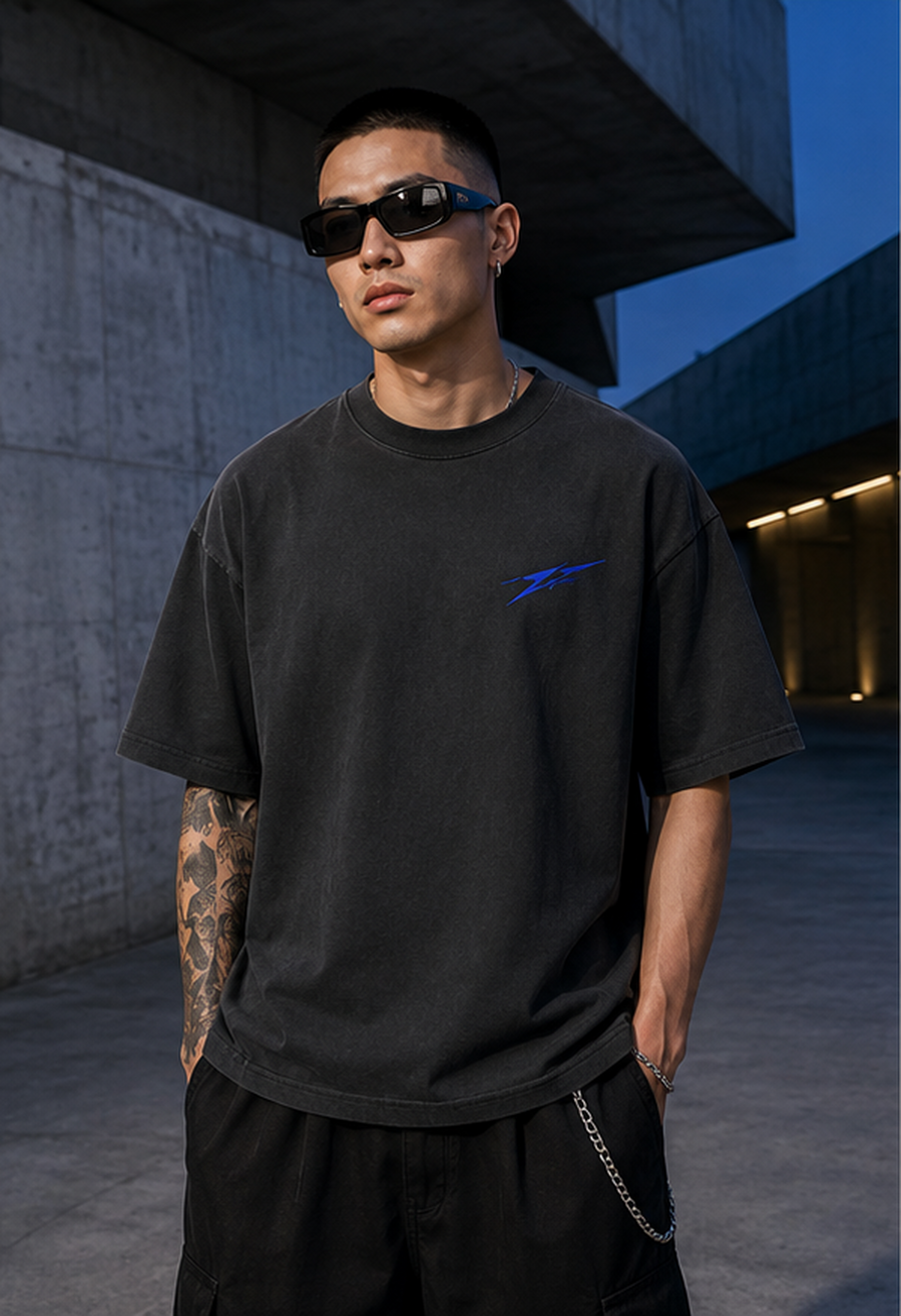 Male model wearing the charcoal Asphalt Echo oversized graphic tee in a concrete city passage