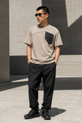 Male model wearing the stone Concrete Halo boxy utility tee in a modern plaza
