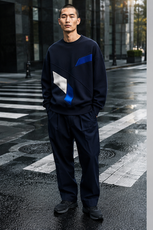 Male model wearing the navy Crosswalk Core oversized crewneck on a rain-dark crosswalk