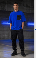 Male model wearing the cobalt Signal Drift utility pocket tee in a parking structure